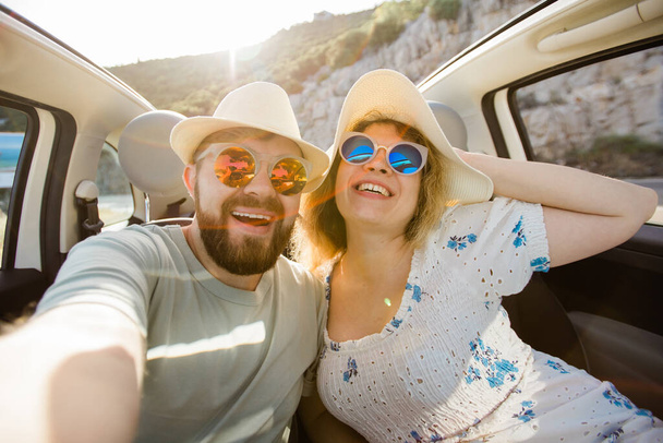 Heureux beau couple amoureux de prendre un portrait selfie au volant d'une voiture convertible sur la route en vacances. Location de voitures et concept de vacances - Photo, image