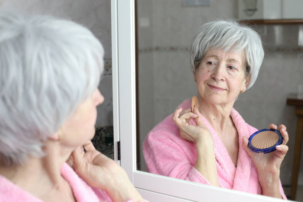Banyoda aynanın karşısında olgun bir kadının yakın plan portresi. - Fotoğraf, Görsel