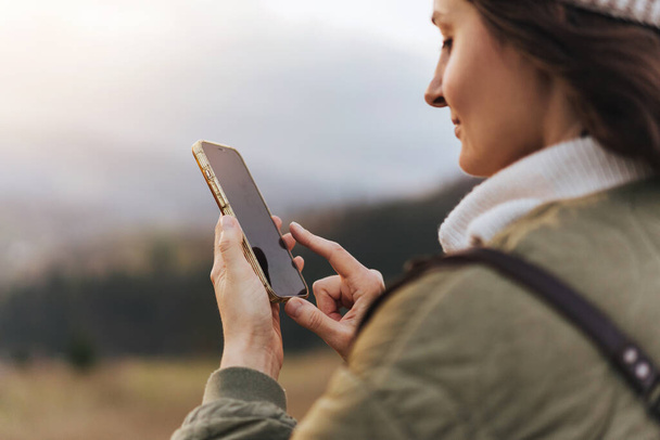 Crop kép női utazó segítségével online térkép mobiltelefon túrázás közben az erdőben, női kéz kezében modern mobiltelefon szerkentyű és ujjal mutogatás - Fotó, kép