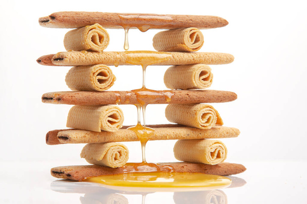 Le miel de fleur frais coule et goutte sur des bâtonnets de biscuits croustillants herbacés. Dessert snack-food. - Photo, image