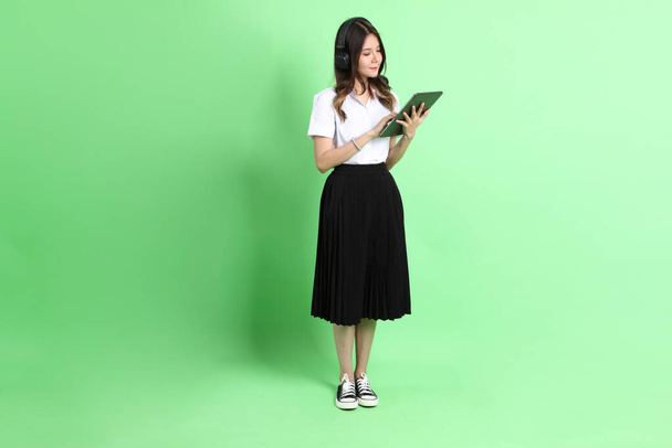The young school girl with uniform standing on the green background. - Foto, Imagem