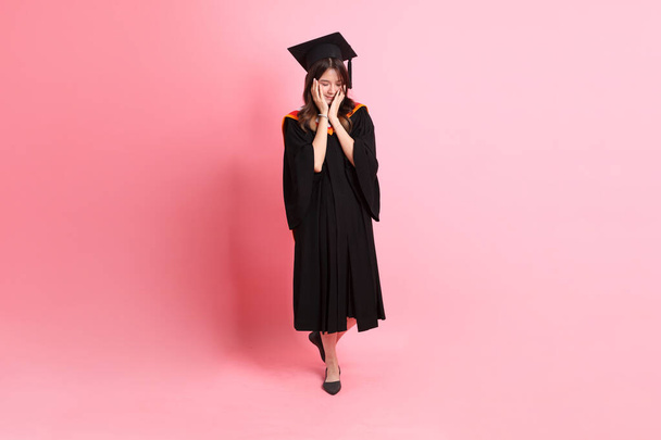 La mujer asiática en vestido de graduación de pie sobre el fondo rosa. - Foto, imagen