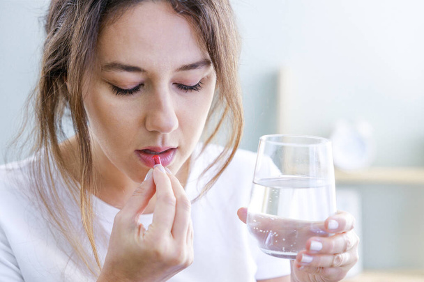 Sick woman using antibiotics with glass of water in her hands - Foto, Imagem