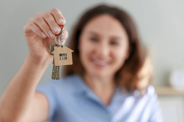 Cheerful young woman moving into new house showing her keys - Photo, Image