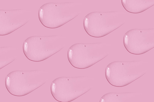 O fundo é cosmético. Muitas manchas de gel transparente em um fundo rosa. - Foto, Imagem