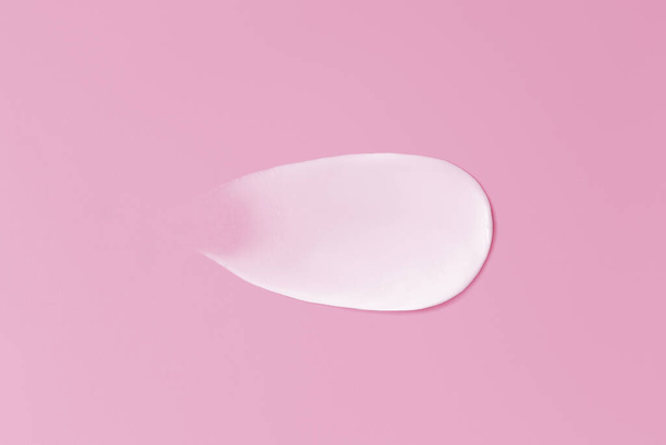 Close-up smear of cream texture on a pink background - Foto, Imagen