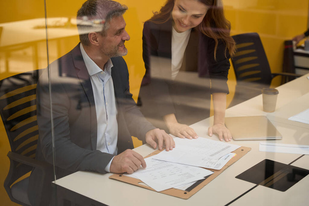 Közelkép kép felnőtt férfi és fiatal nő megvitatása szerződést az asztalnál az üzleti központban - Fotó, kép