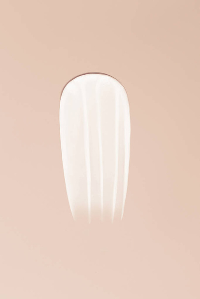 Frotis de primer plano de textura crema sobre un fondo beige - Foto, imagen