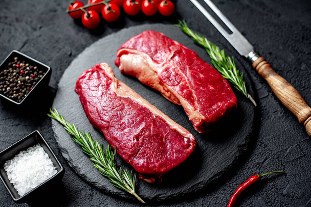 steak de bœuf cru aux épices et herbes sur fond de pierre noire - Photo, image