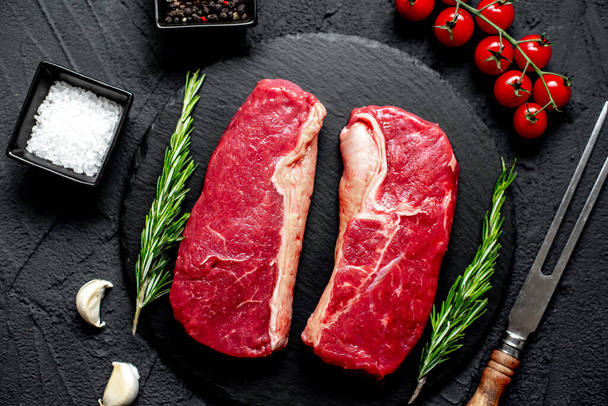 steak de bœuf cru aux épices et herbes sur fond de pierre noire - Photo, image