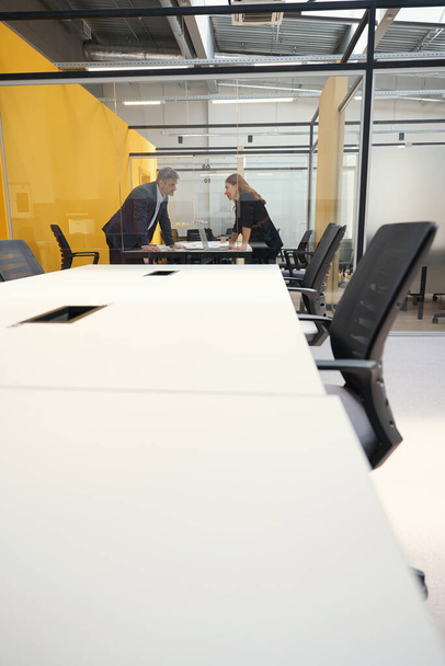 Hombre y mujer adultos de pie en la mesa y mirándose unos a otros en el centro de negocios - Foto, imagen