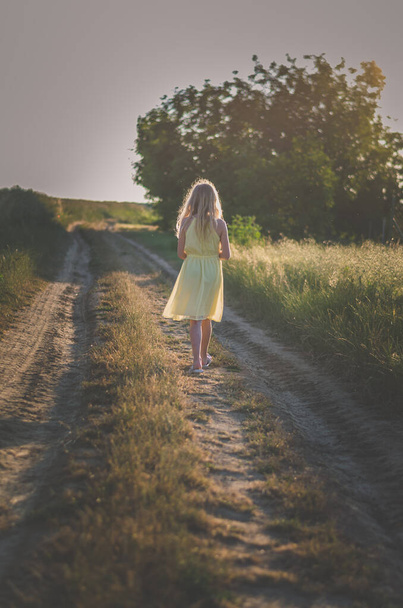 adorable girl with long blond hair in rural path in summer atmosphere  - 写真・画像