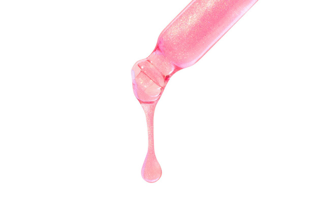 Pipeta com líquido gotejante de cor rosa com brilhos. Ou ouro rosa líquido. Isolado sobre um fundo branco. - Foto, Imagem