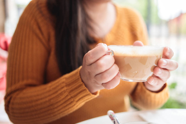Улыбающаяся молодая женщина пьет кофе во внутреннем дворике кафе и болтает с другом в пасмурный день. Высокое качество фото - Фото, изображение