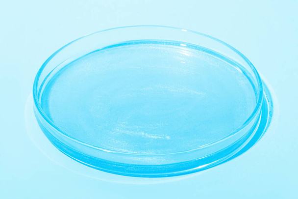 Blue liquid with luster. In a Petri dish. Laboratory research of cosmetics, gel, medicine. Chemistry - Фото, зображення