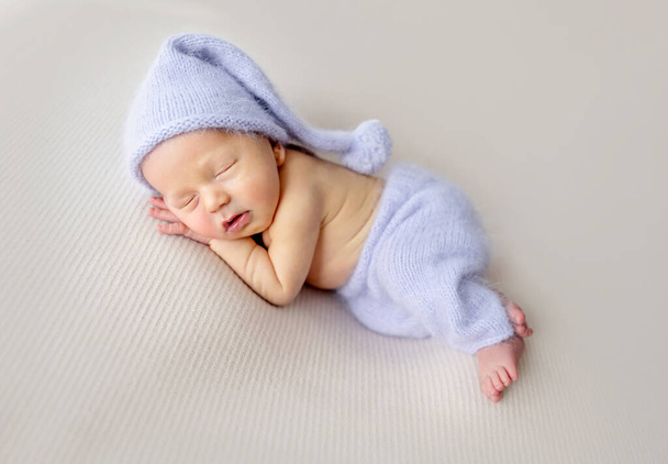 Newborn baby boy with bunny toy sleeping wearing knitted pants and hat. Little infant child napping - Fotoğraf, Görsel