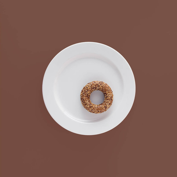 Homemade sesame and flax seed bagel on round white plate against maroon-brown isolated background. Minimal flat lay. Modern food pattern. Bakery concept. - Photo, image