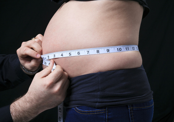 A pregnant woman measuring her belly over white background - Fotoğraf, Görsel