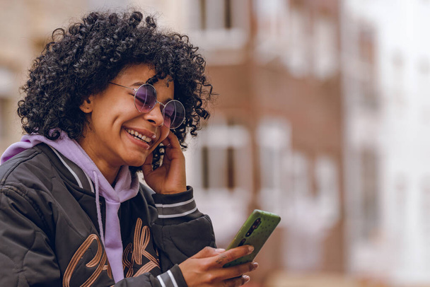 afro dziewczyna na ulicy patrząc na telefon komórkowy - Zdjęcie, obraz
