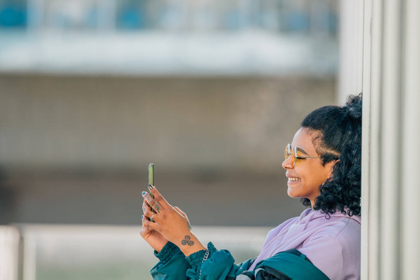 fille dans la rue avec téléphone portable sur le mur avec copie-espace - Photo, image