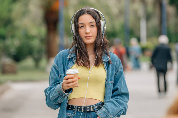 girl walking with headphones and cup of coffee - Фото, изображение