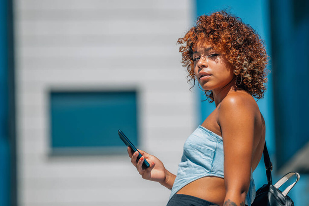 latin fekete lány mobiltelefon az utcán, városi stílusban - Fotó, kép