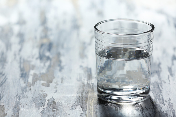 Glass of clean mineral water on old color wooden background - Fotó, kép