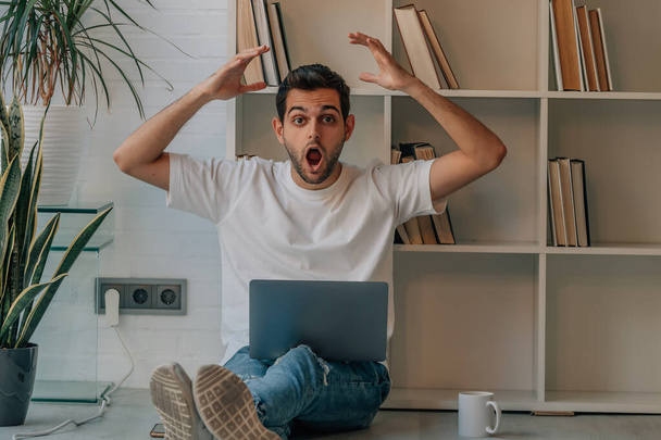 young man at home with laptop with surprise expression and reaction - Photo, Image