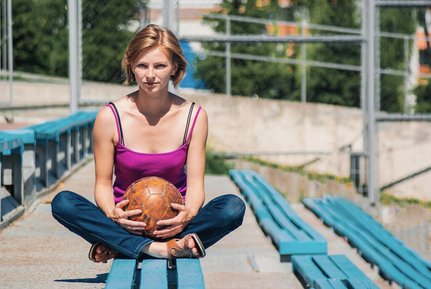 dun jong meisje op een blauwe bank op een sport stand. - Foto, afbeelding