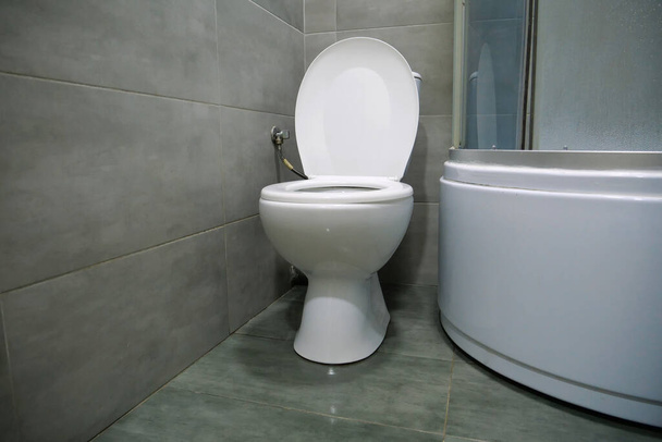 Интерьер туалета с белой унитазом, душевой кабиной и серой плиткой для стен - Фото, изображение