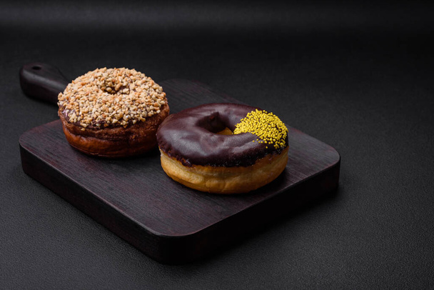 Delicious donut with cream filling and nuts on a dark concrete background. Sweet junk food - Photo, Image