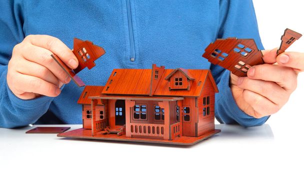 Der Mensch baut mit seinen Händen ein Modell eines Hauses zusammen. Konzept für den Bau eines Wohnhauses - Foto, Bild