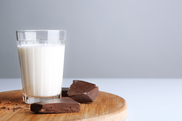 Süt beyaz izole ahşap kesme tahtası üzerinde çikolata parçaları ile - Fotoğraf, Görsel