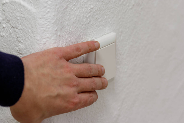 un interruptor de luz, un interruptor mecánico de plástico de color blanco instalado en una pared blanca. - Foto, Imagen