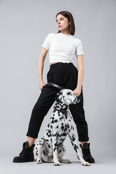 Beautiful young woman with her adorable Dalmatian dog on light grey background. Lovely pet - Fotoğraf, Görsel