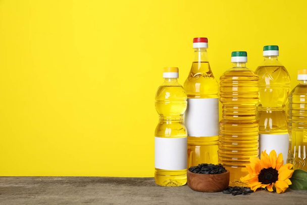 Bottles of cooking oil, sunflower and seeds on wooden table, space for text - Valokuva, kuva