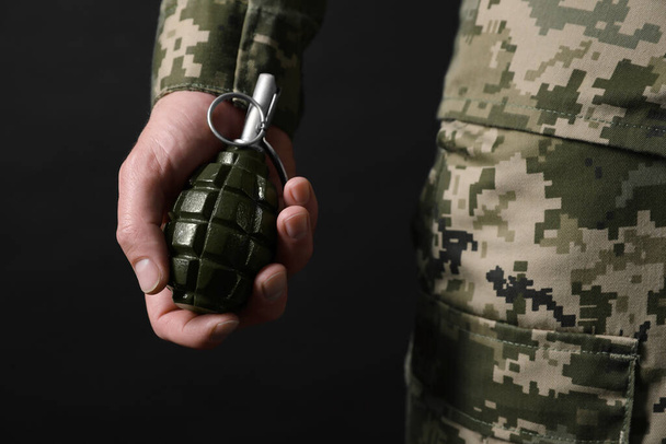 Soldier holding hand grenade on black background, closeup. Military service - Foto, afbeelding