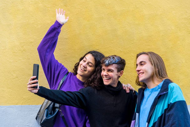 Young diverse friends taking selfies with a mobile phone outdoors. Technology and Lgbt concept. - Foto, immagini