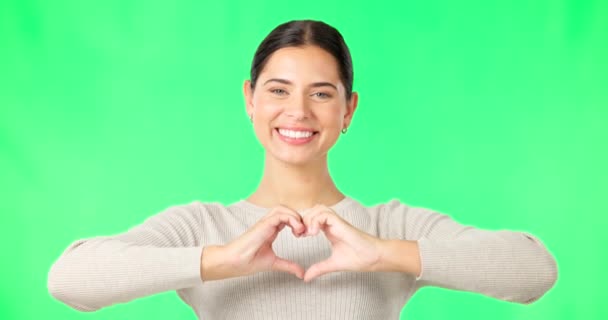 Heart, hands and face of happy woman on green screen, studio and color backdrop. Portrait of female model, finger shape and love of support, thank you and emoji sign of kindness, care and peace icon. - Footage, Video