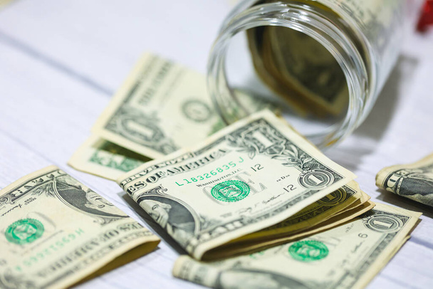 Bons du dollar américain sur une table en bois avec un bocal en verre en macro photographie. Concept d'économie. - Photo, image