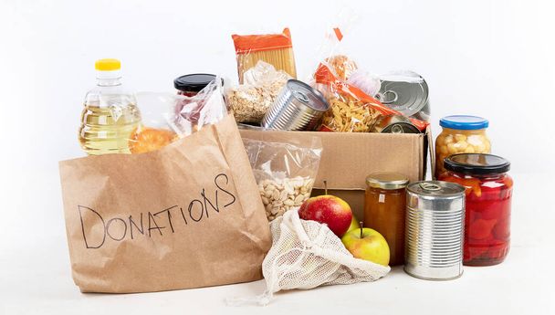 Food donation box of different products  on light background, top view. Food donations or delivery concept. - Foto, Imagen