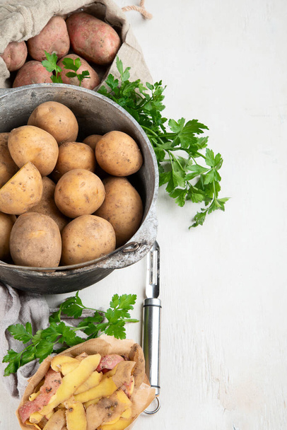 Raw potato food. Fresh potatoes in an old cooking pot on a white background. Top view. Copy space. - Foto, afbeelding