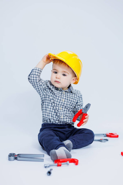 Милий хлопчик у сорочці на зображенні будівельника, на білому тлі. Дитинство, навчання, робота, ігри, кар'єра, імітація. Маленький тато помічник
. - Фото, зображення