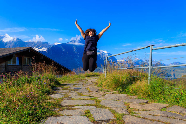 Donna felice saltare e godersi la vita in montagna. Località Alpi svizzere, valle del Grindelwald, Svizzera. Viaggio e stile di vita attivo - Foto, immagini