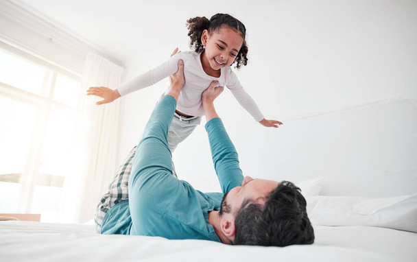 Fun, playing and a dad holding a child, bonding and pretending to fly in a bedroom. Happy, playful and a little girl flying, feeling free and spending quality time with a father for play at home. - Foto, Bild