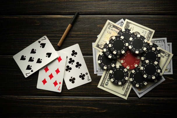 Играя в карты с выигрышной комбинацией из трех видов или набор и деньги с чипсами на черном винтажном столе. Победа в спорте или покере зависит от удачи. - Фото, изображение