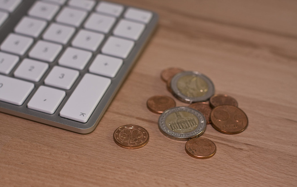 Клавиатура и монеты евро на деревянном столе
 - Фото, изображение