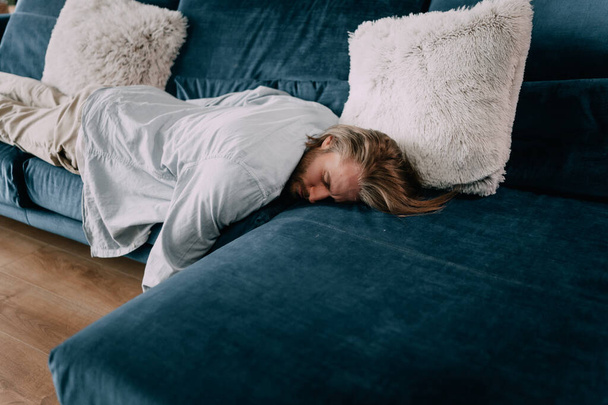 Exhausted young man fell asleep on comfortable couch in modern living room, having no energy after hard working day. Tired depressed unmotivated caucasian guy napping on sofa at home, fatigue concept - Fotoğraf, Görsel