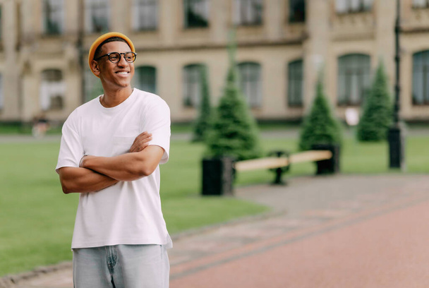 A portrait of an African American cstudent with glasses smiling with the university on the background. - Foto, imagen