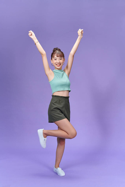 Full length view of blissful asian girl with hands up on purple background. - Foto, Imagen